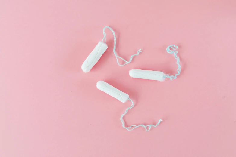 a couple of toothbrushes laying on top of a pink surface, by Elsa Bleda, trending on pexels, plasticien, garters, membrane pregnancy sac, milk cubes, hanging from white web