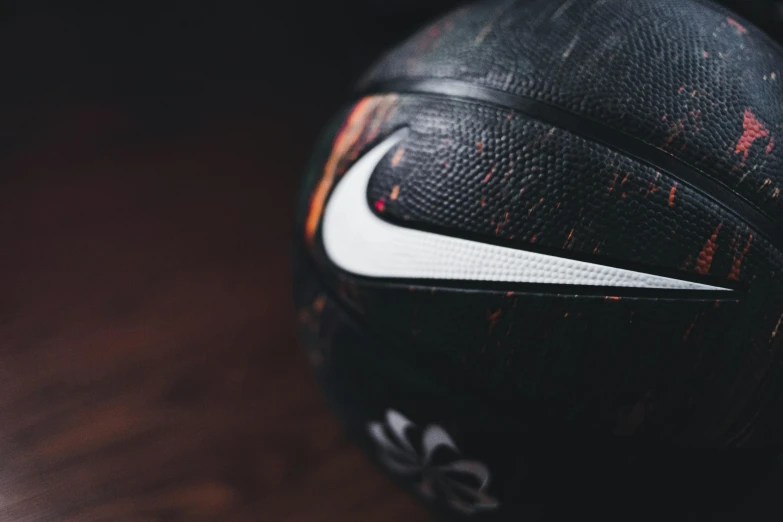 a close up of a basketball ball on a table, inspired by Mia Brownell, trending on dribble, black orb of fire, nike logo, shot on hasselblad, some grungy markings