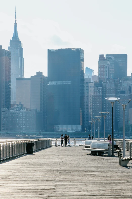 a couple of benches sitting on top of a wooden pier, by Tom Wänerstrand, trending on unsplash, modernism, new york skyline, slide show, early 2 0 0 0 s, all buildings on bridge