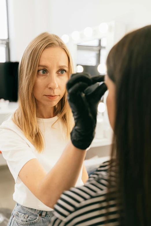 a woman getting her hair done in front of a mirror, by Adam Marczyński, shutterstock, portrait of a female pathologist, wearing eye shadow, a blond, thumbnail