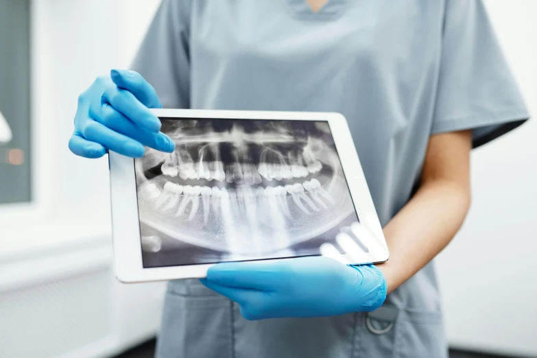 a close up of a person holding a tablet, uniform teeth, xray, where a large, uploaded