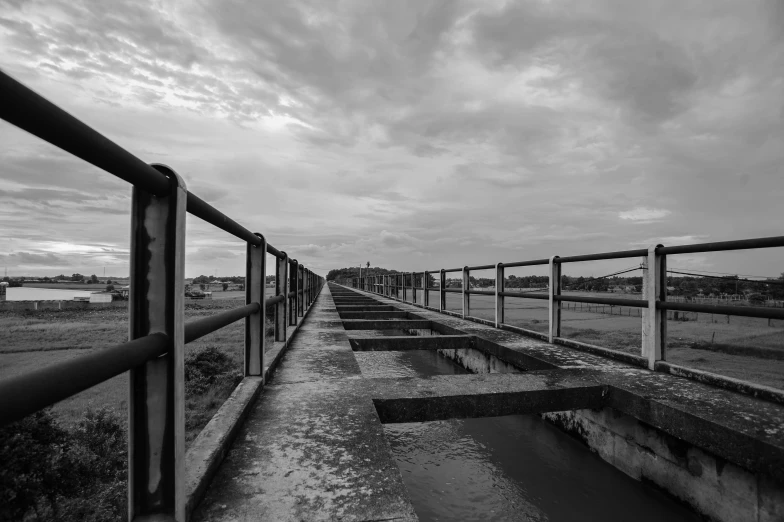 a black and white photo of a bridge, a black and white photo, unsplash, sewage, dramatic sky, water reservoir, maintenance photo