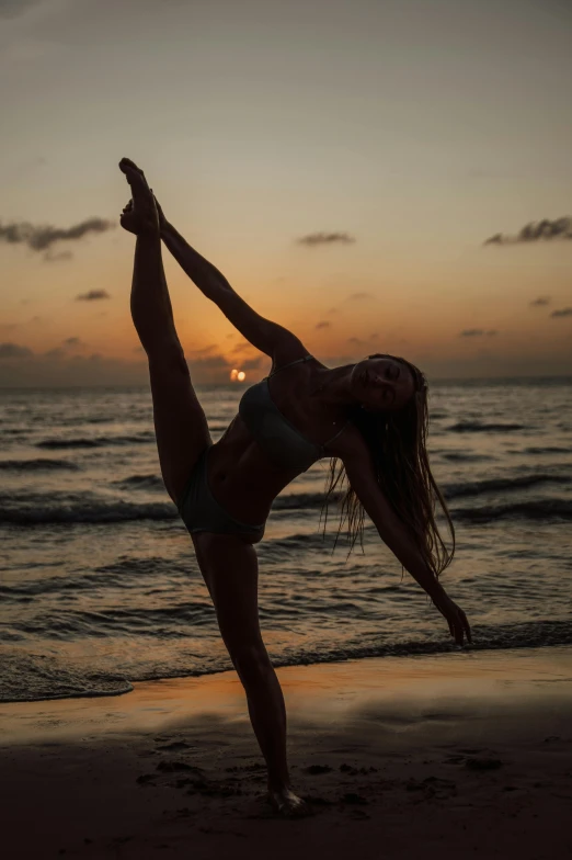 a woman doing a yoga pose on the beach, a picture, by Niko Henrichon, pexels contest winner, arabesque, classic dancer striking a pose, dusk setting, kailee mandel, split near the left