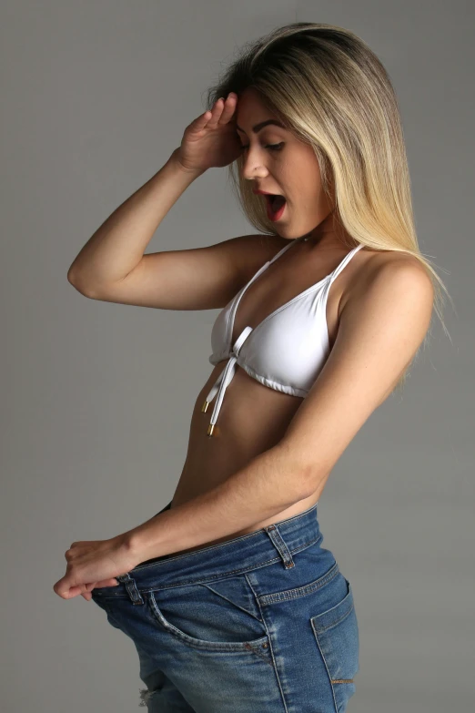 a woman in a white bra top and blue jeans, by Robbie Trevino, pexels contest winner, photorealism, very surprised, young blonde woman, fun pose, gif