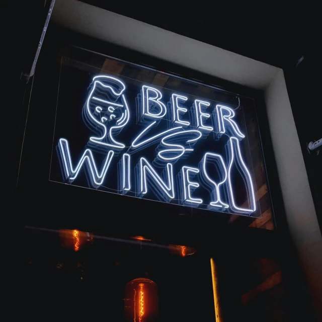a neon sign hanging from the side of a building, wine, beer, 5 feet away, during night