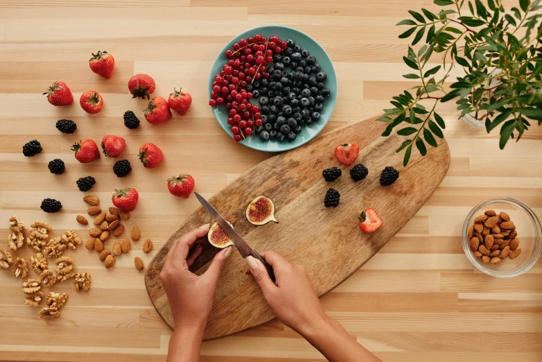 a person cutting fruit on a cutting board, inspired by david rubín, wild berries, overview, tabletop, angled shot