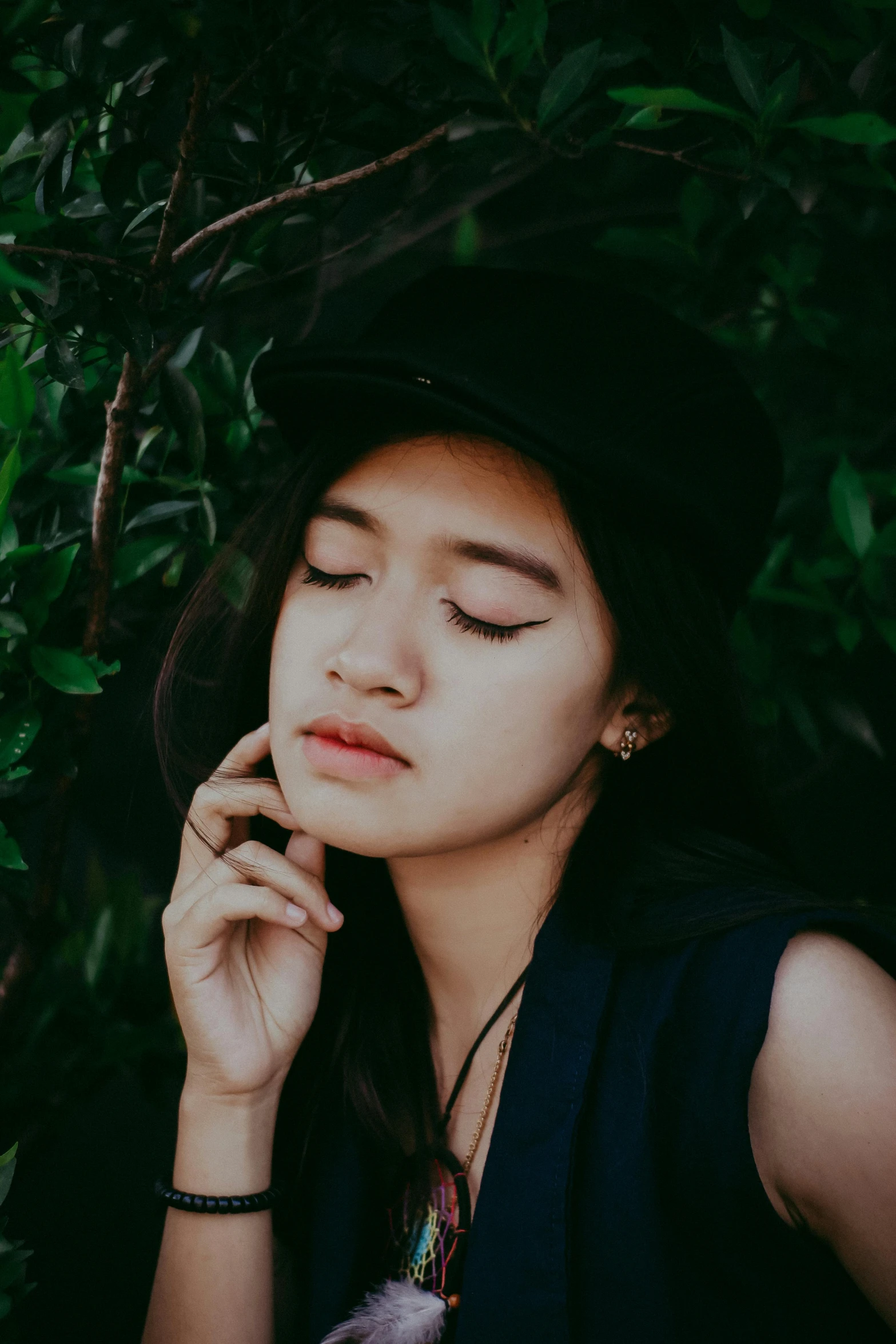 a woman wearing a hat talking on a cell phone, inspired by Ruth Jên, trending on pexels, realism, eyes closed, asian girl, prominent jawline, sitting on a leaf