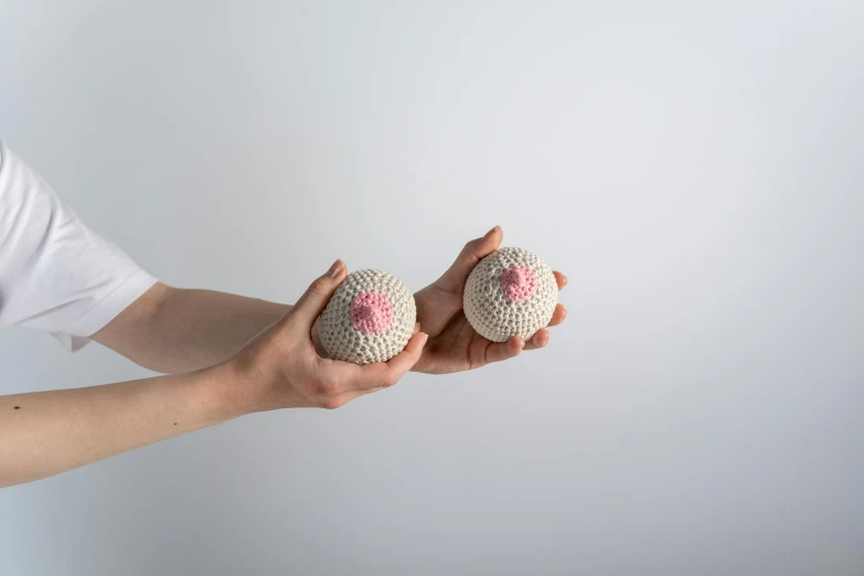 a person holding two crocheted balls in their hands, inspired by Louise Bourgeois, unsplash, covered with pink marzipan, organic ceramic white, front and side view, spores