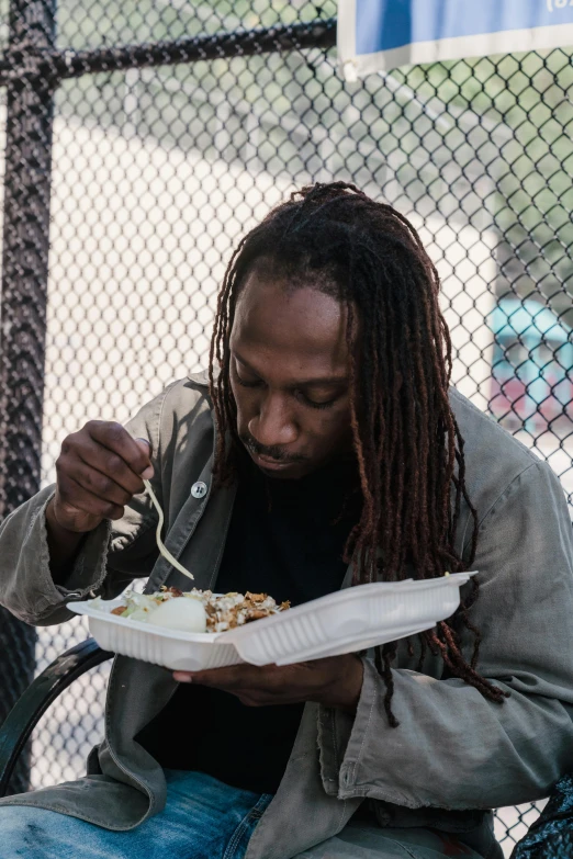 a man sitting on a bench eating food, jamal campbell, over a dish and over a table, gaze down, festivals