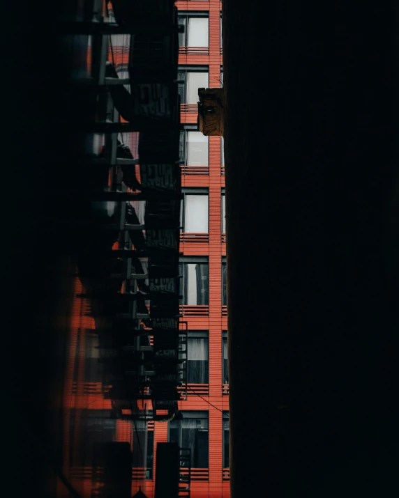 a tall building sitting in the middle of a city, a photo, inspired by Elsa Bleda, unsplash contest winner, graffiti, red on black, balconies, orange hue, new york alleyway