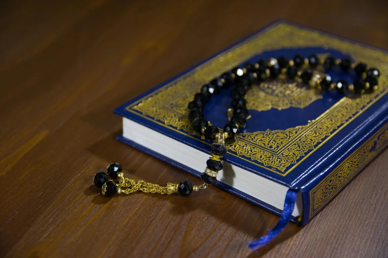 a blue book sitting on top of a wooden table, hurufiyya, beads, reyyan, thumbnail, beautiful image