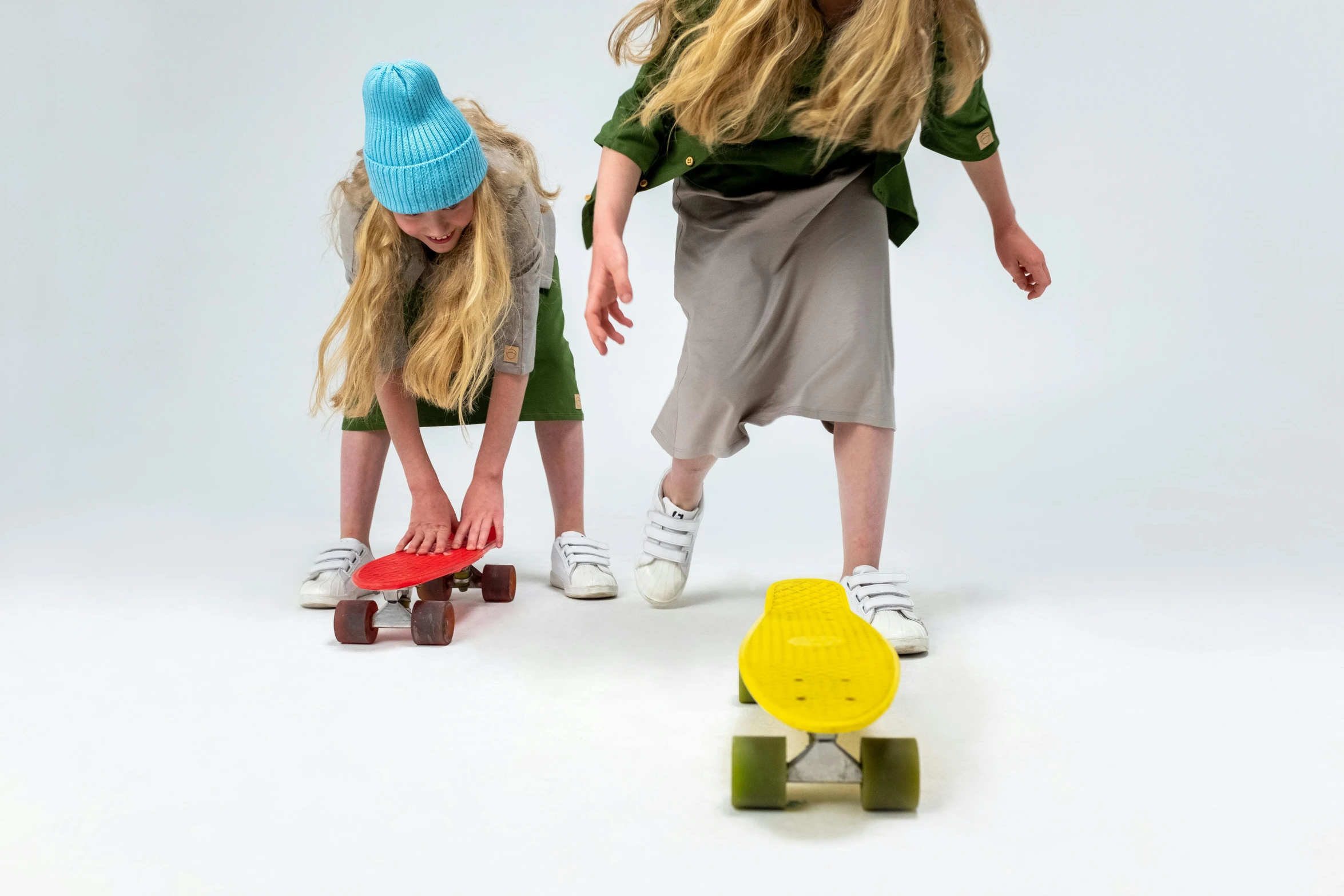 a couple of young girls standing next to each other, inspired by Elsa Beskow, graffiti, standing on a skateboard, solid colours material, yellow and green, high quality product photo