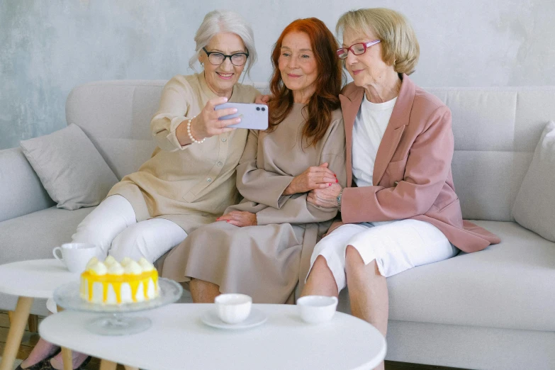 three women sitting on a couch taking a selfie, trending on pexels, an old lady with red skin, elegant scene, sitting on top a table, a very macular woman in white