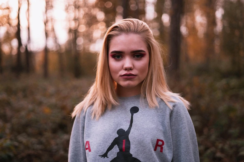 a woman standing in the middle of a forest, a character portrait, inspired by Elsa Bleda, unsplash, realism, basketball, grey sweater, red, portrait of kim petras