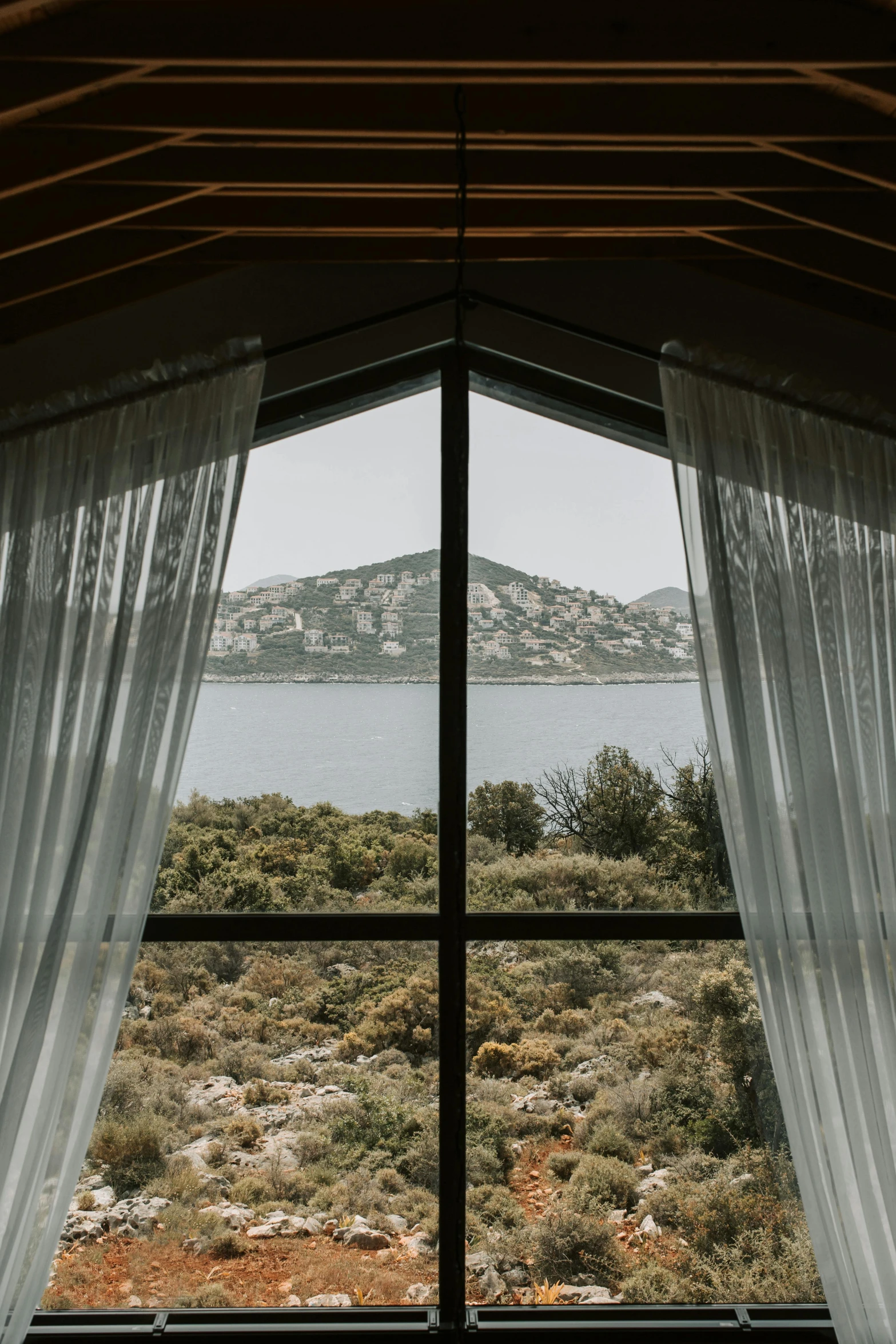 a bedroom with a view of a body of water, by Yerkaland, trending on unsplash, beaded curtains, roof with vegetation, turkey, symmetrical outpost