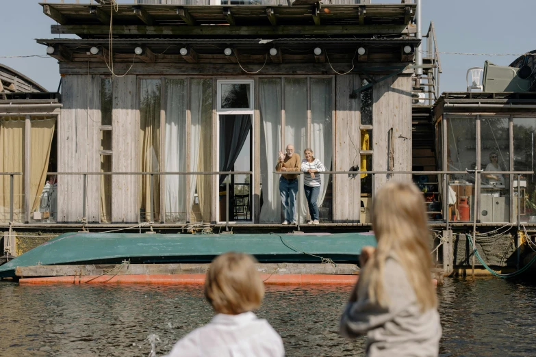 a couple of people standing on top of a boat, by Jan Tengnagel, happening, lake house, 3 actors on stage, urban surroundings, family friendly