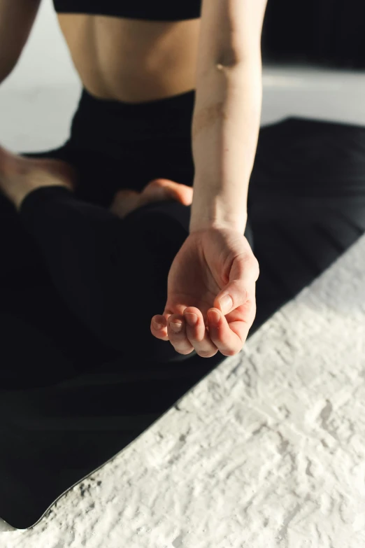 a woman sitting in a yoga position on a bed, unsplash, visual art, close-up of thin soft hand, his arms spread, with index finger, low quality photo