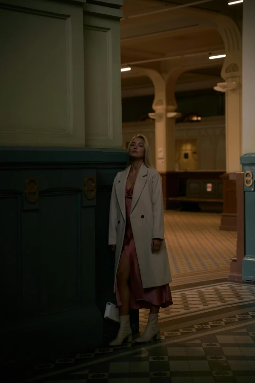 a woman standing in front of a clock in a building, inspired by Gordon Parks, unsplash, hyperrealism, detective coat, perfectly lit. movie still, official vogue editorial, betty cooper