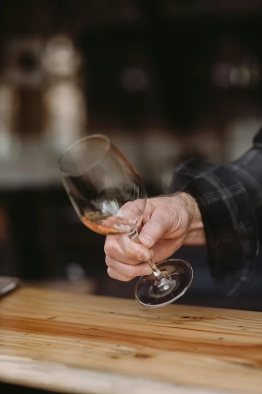 a close up of a person holding a wine glass, by Jesper Knudsen, whisky, well built, creating a soft, hands on counter