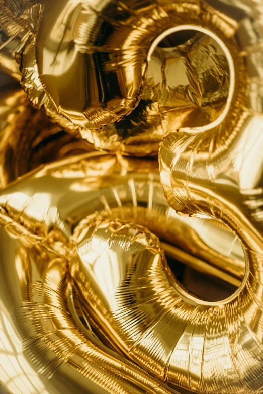 a bunch of gold foil balloons sitting on top of a table, an abstract sculpture, by Nina Hamnett, trending on pexels, gold rings, close up. macro. hyper realistic, golden thread, mario testino