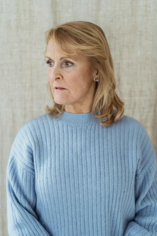 a woman in a blue sweater posing for a picture, by Helen Biggar, concerned expression, promotional image, marianne collins, white and pale blue