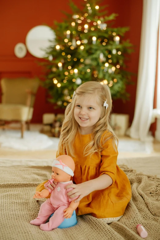 a little girl sitting on the floor with a doll, inspired by Carl Larsson, shutterstock contest winner, festive atmosphere, with a tree in the background, official product photo, amber glow
