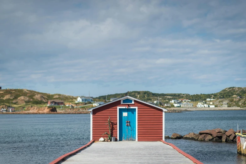 a red boathouse sitting on a dock next to a body of water, a portrait, pexels contest winner, private press, picton blue, hziulquoigmnzhah, notan, fishing village