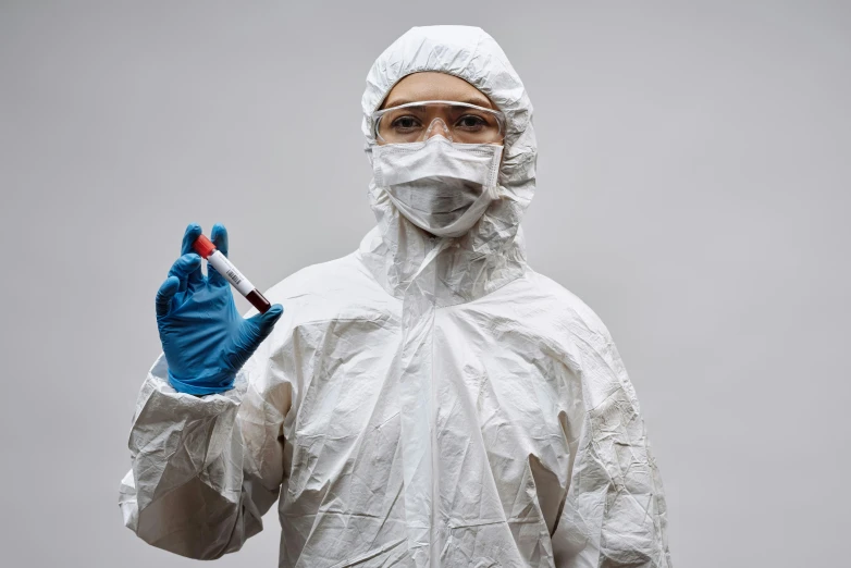 a man in a protective suit holding a test tube, by Adam Marczyński, pexels contest winner, portrait of a female pathologist, on a gray background, plastic and fabric, thumbnail