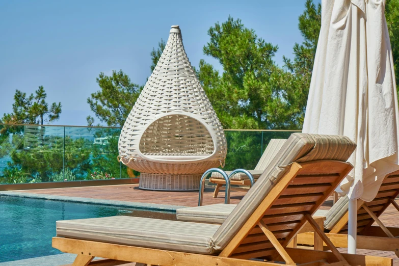 a couple of lounge chairs sitting next to a swimming pool, a portrait, inspired by Exekias, pexels contest winner, pine treehouse, cone shaped, seaside, closeup - view