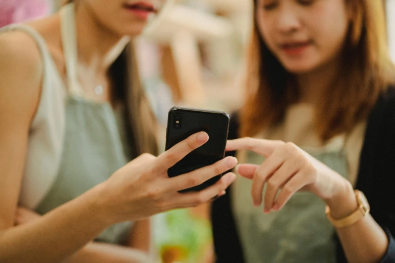 two women are looking at a cell phone, trending on pexels, square, 1 2 9 7, fan favorite, mid shot