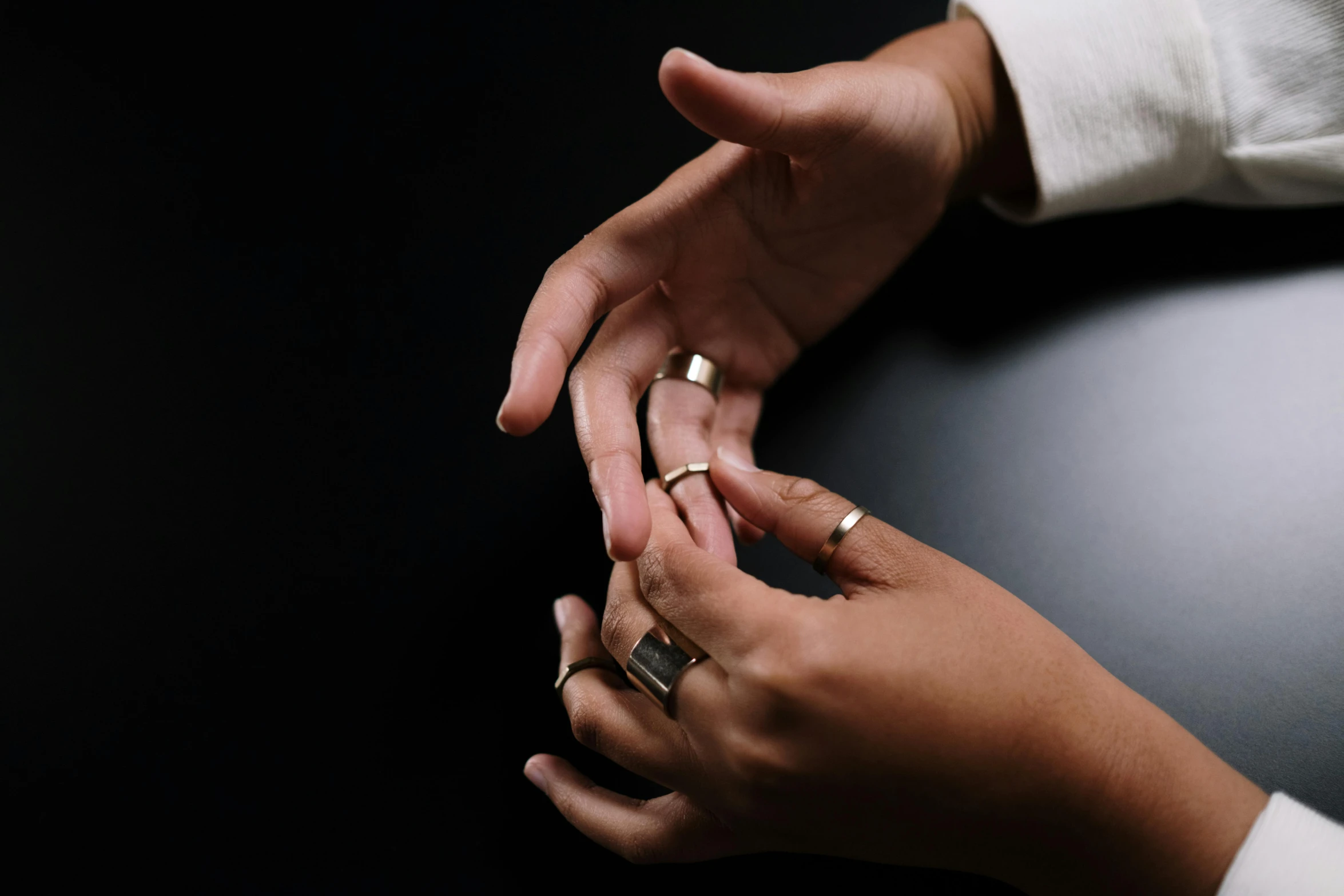 a close up of a person holding a cell phone, gold rings, hands reaching for her, dark and white, creterion collection