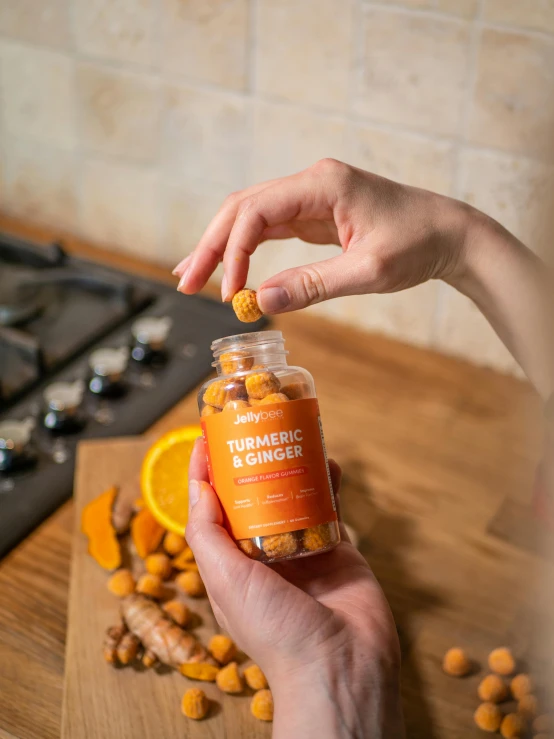 a close up of a person holding a bottle of food, a picture, very orange, ingredients on the table, highly capsuled, ginger
