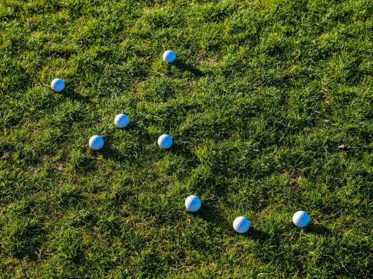 a group of golf balls sitting on top of a lush green field, a stock photo, by Jan Rustem, unsplash, precisionism, shadows, crop circles, corners, marble!! (eos 5ds r