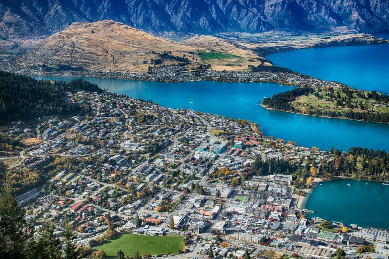 a city in the middle of a lake surrounded by mountains, new zeeland, flatlay, vivid and vibrant, zoomed out to show entire image