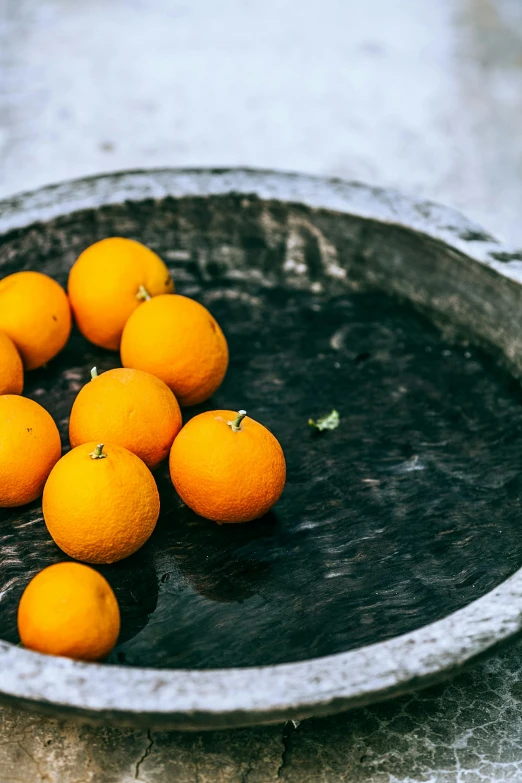 a bowl filled with oranges sitting on top of a table, by David Garner, trending on unsplash, water feature, moroccan, grey, organic detail