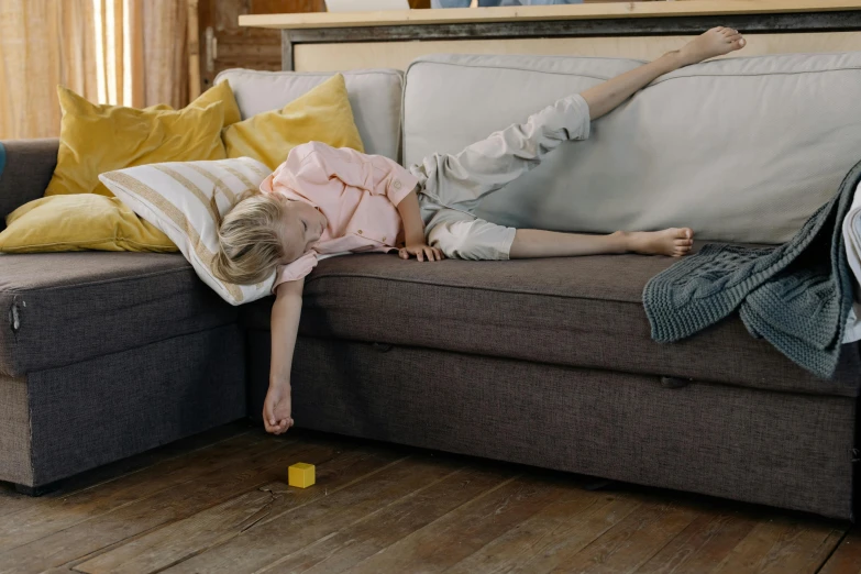 a little girl laying on top of a couch, inspired by Sarah Lucas, pexels contest winner, wipe out, casual game, broken furniture, with yellow cloths