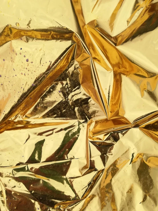 a piece of foil sitting on top of a table, an album cover, inspired by John Chamberlain, trending on unsplash, hyperrealism, gold bodypaint, ignant, gold and purple, folds