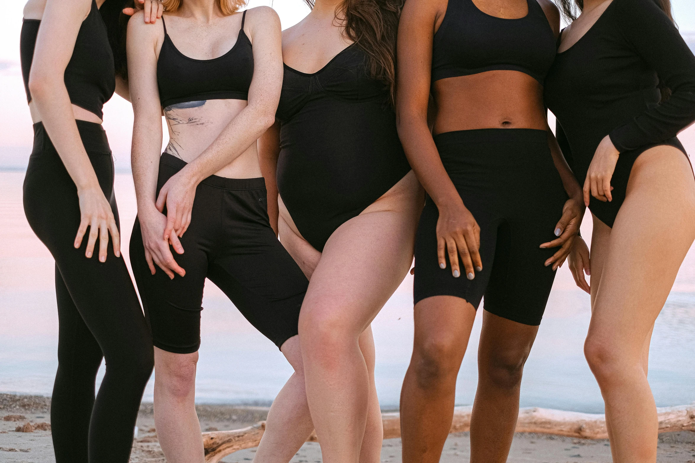 a group of women standing next to each other on a beach, inspired by Vanessa Beecroft, trending on pexels, renaissance, black spandex, crop yoga short, panel of black, thighs close up