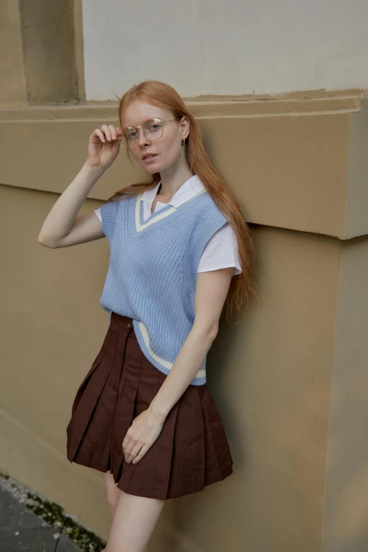 a woman leaning against a wall while talking on a cell phone, trending on reddit, renaissance, wearing school uniform, brown and cyan blue color scheme, at a fashion shoot, uncanny valley