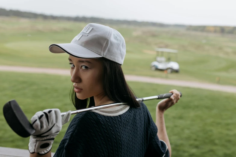 a woman holding a golf club in one hand and a golf ball in the other, a portrait, unsplash, happening, with rap cap on head, chinese girl, off - white collection, full product shot