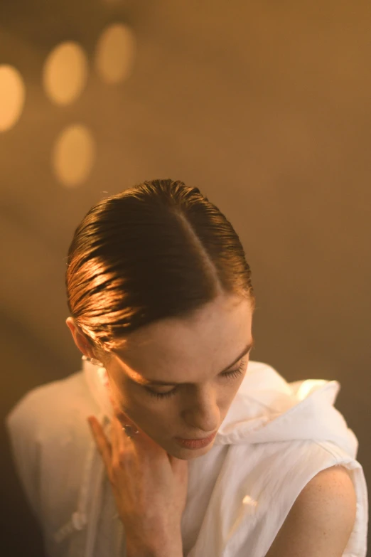 a woman sitting at a table with a plate of food, an album cover, inspired by Nan Goldin, unsplash, bauhaus, closeup of sweating forehead, slicked back hair, studio soft lighting, bathed in golden light