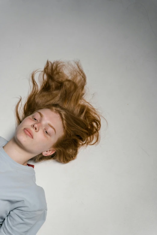 a woman with her hair blowing in the wind, trending on pexels, renaissance, lying down, red haired teen boy, on a pale background, flattened