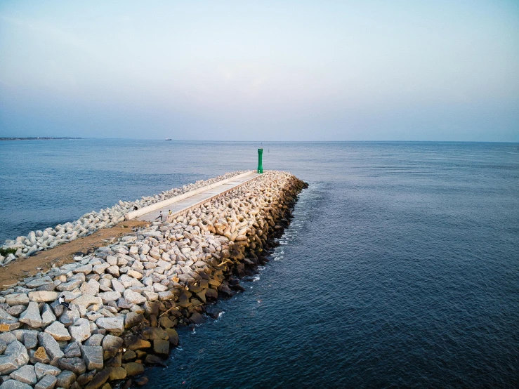 a lighthouse in the middle of a body of water, unsplash, minimalism, landscape architecture photo, near a jetty, long distance photo, rocky seashore