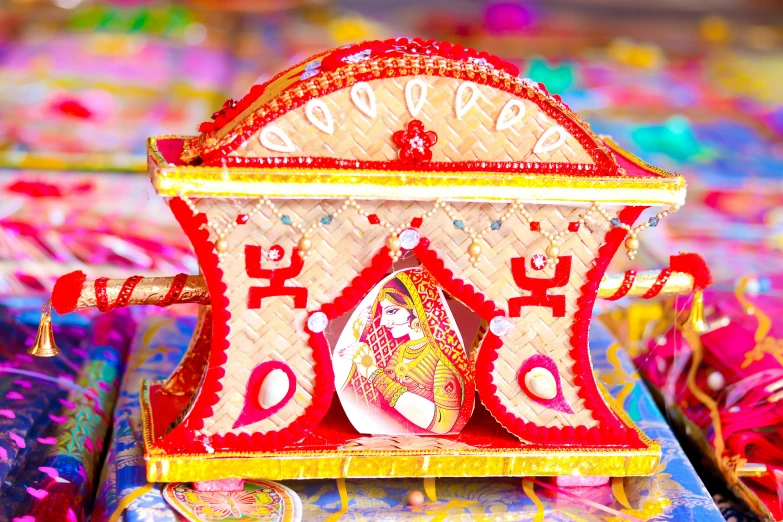 a decorative clock sitting on top of a table, a picture, by Julia Pishtar, samikshavad, celebrating an illegal marriage, red and gold sumptuous garb, hut, thumbnail