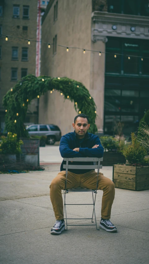 a man sitting on a bench in front of a building, joel torres, sitting in fancy chair, centered full-body shot, riyahd cassiem