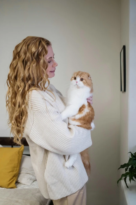 a woman holding a cat in her arms, trending on reddit, ginger wavy hair, wearing turtleneck, profile image, high resolution photo