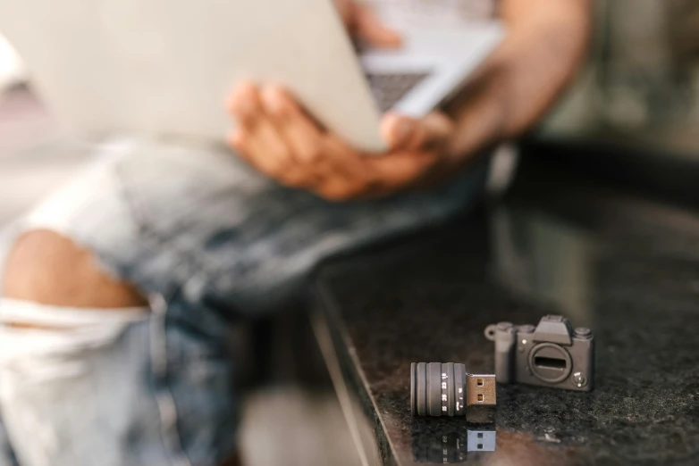 a man sitting on top of a counter next to a laptop, a picture, unsplash, visual art, photo kodak lens, toy photography, close up shot a rugged, usb ports