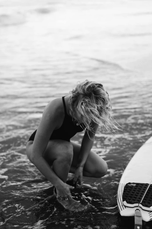 a woman kneeling on a surfboard in the water, a black and white photo, unsplash, a blond, a messy, kai carpenter, mixing