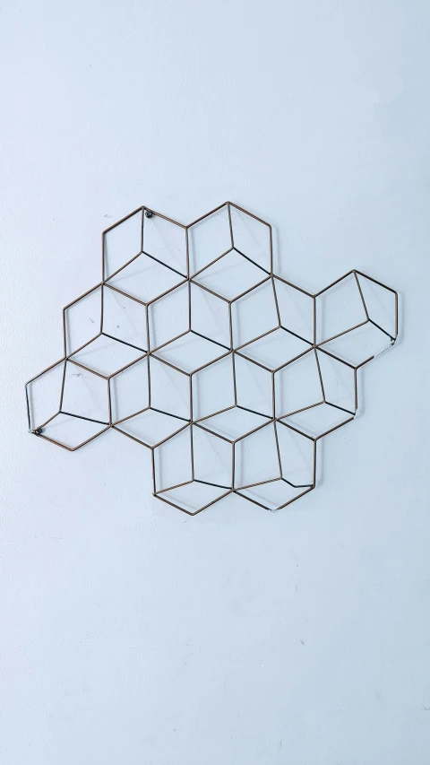 a close up of a metal object on a white surface, inspired by Buckminster Fuller, unsplash, wall art, brown, squares, hive