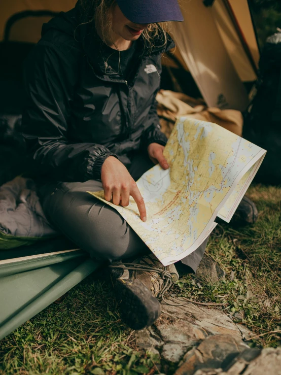 a woman sitting on the ground looking at a map, by Jessie Algie, trending on unsplash, camping, straight on portrait, low detail, 🚿🗝📝